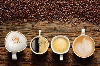 Variety of cups of coffee and coffee beans on old wooden table